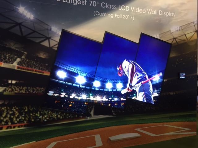 Uma parede de vídeo formada por 3 painéis de vídeo LCD de 70 polegadas, exibindo um jogador de beisebol em um estádio