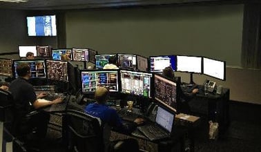 Uma sala de controle com trabalhadores em seus postos de trabalho