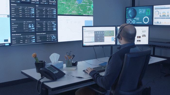 GIF de funcionário de logística digitando em sua mesa de escritório em frente a uma parede de vídeo, depois remotamente de sua mesa de casa em frente a uma janela