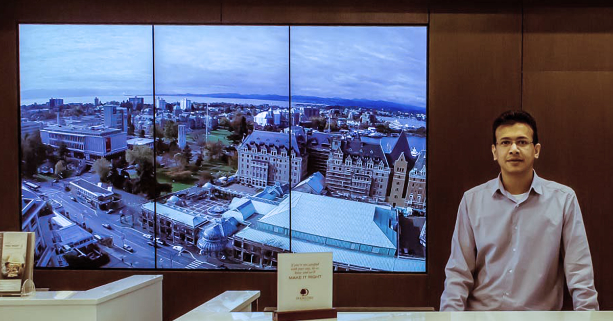 DoubleTree by Hilton receptionist and 3 panel video wall behind him displaying landmarks from Victoria, Canada