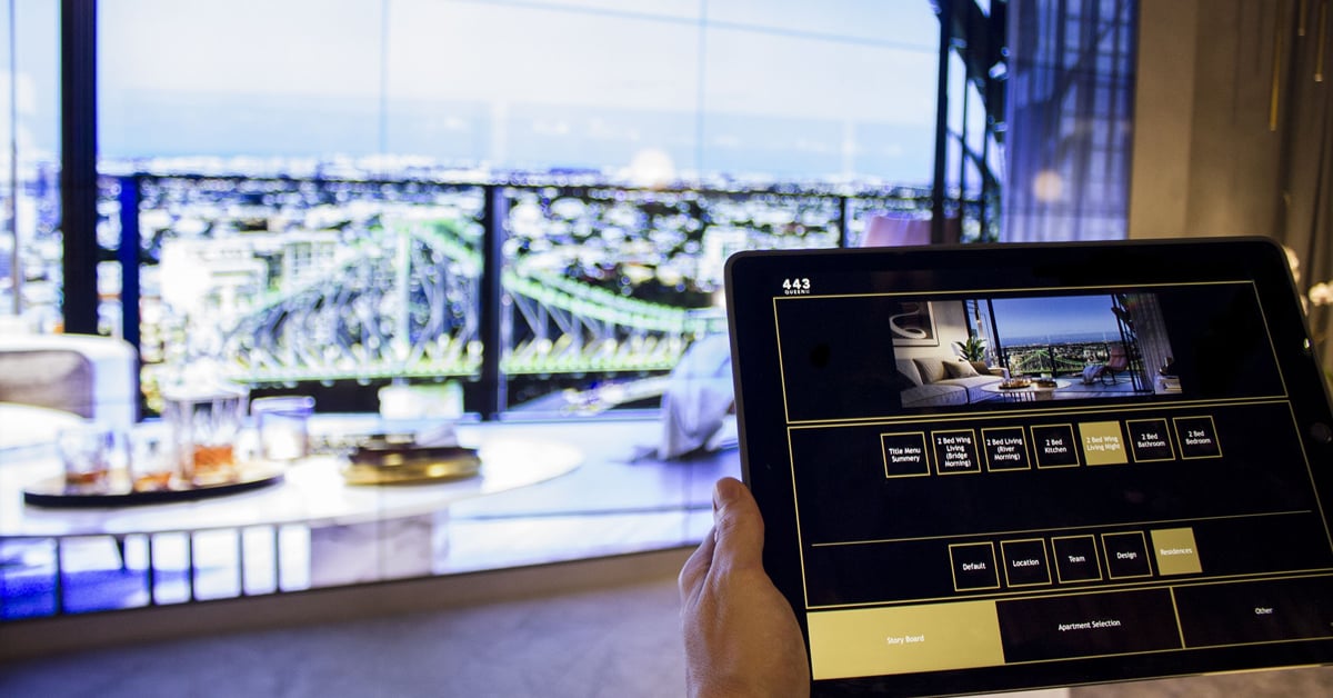 Q1 Escritório de Vendas de Design na Austrália, com uma parede de vídeo exibindo fotos de propriedades, selecionadas em uma interface tablet