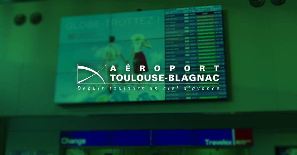 Mural de vídeo no Aeroporto de Toulouse-Blagnac exibindo anúncios e horários de partida para vôos com sobreposição verde e logotipo