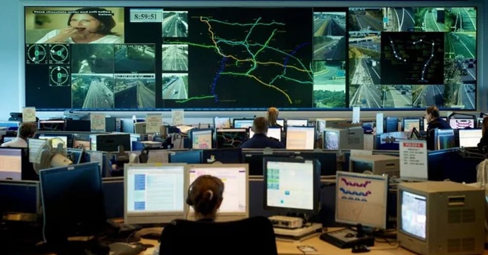 Centro de Operação de Emergência, com paredes de vídeo exibindo câmeras e rotas de tráfego ao vivo, e funcionários trabalhando em estações de trabalho