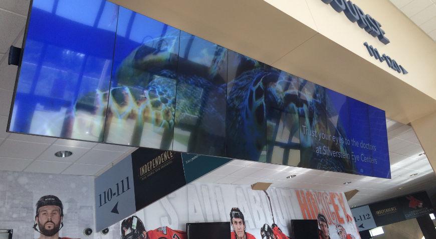 Pendurar uma parede de vídeo em um shopping center exibindo um anúncio para Silverstein Eye Centers