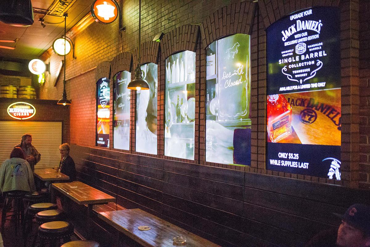 Paredes de vídeo em estilo janela no Smokin' Joe's Pub, exibindo anúncios e arte visual