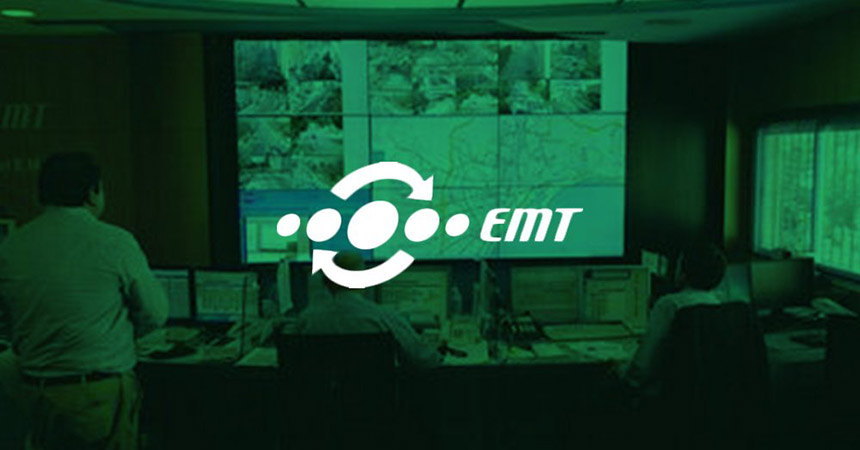 Funcionários da EMT monitorando operações de trânsito através de suas estações de trabalho e uma parede de vídeo exibindo imagens de câmeras ao vivo, mapas de trânsito e sites da Web com sobreposição verde e logotipo