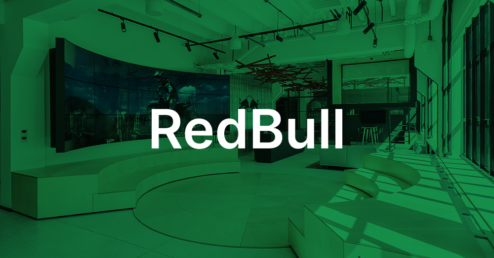 Sede da Redbull Polônia Lobby, com escadaria em forma de escada, mesa de recepção e uma parede de vídeo curva exibindo um comercial da Red Bull com sobreposição verde e logotipo