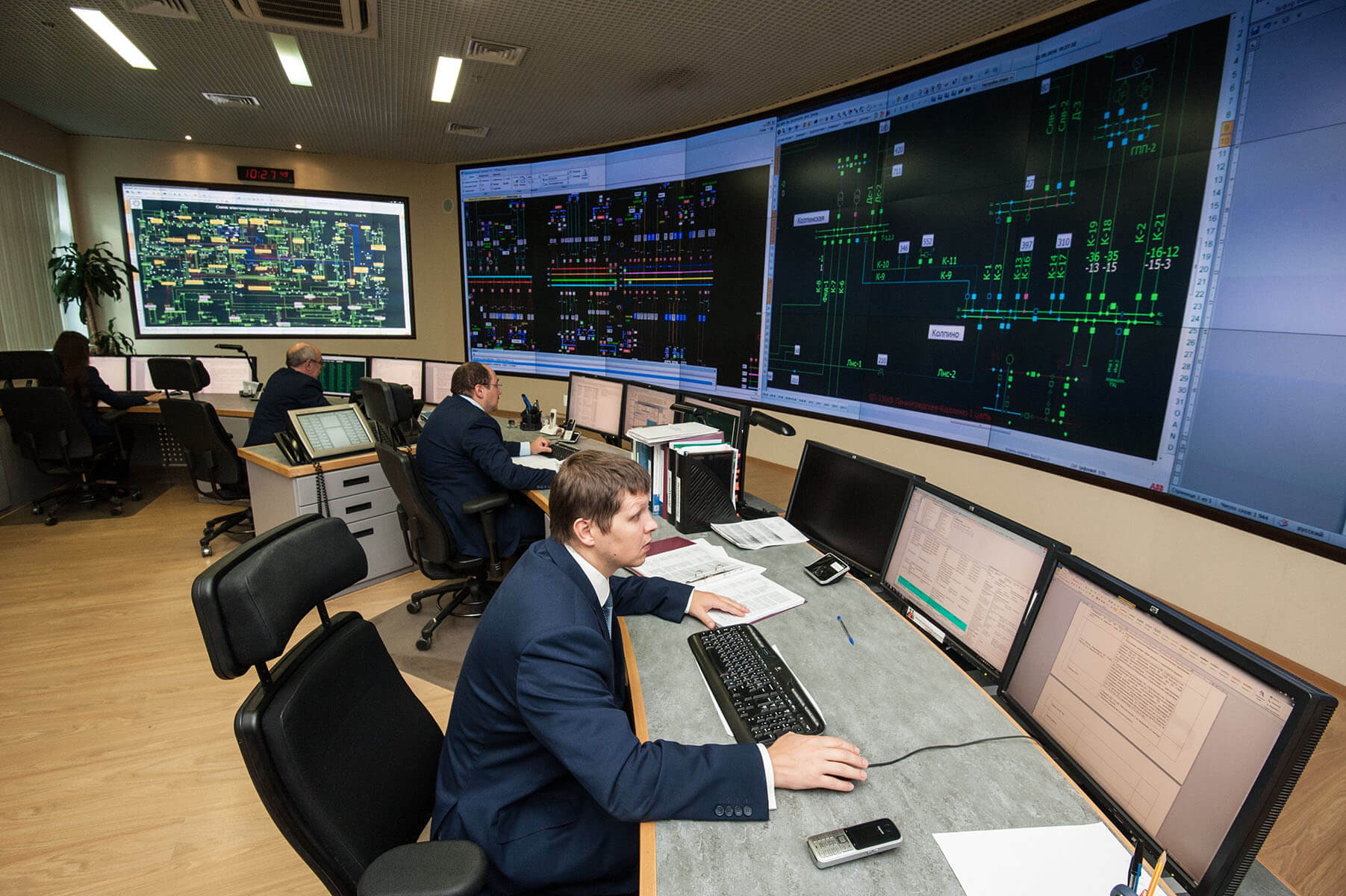 Funcionários que trabalham em uma sala de controle em estações de trabalho com paredes de vídeo exibindo dados de infra-estrutura de TI