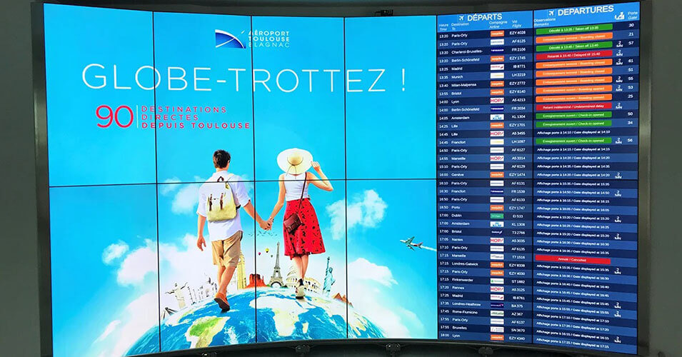Mural de vídeo no Aeroporto de Toulouse-Blagnac exibindo anúncios e horários de partida de vôos